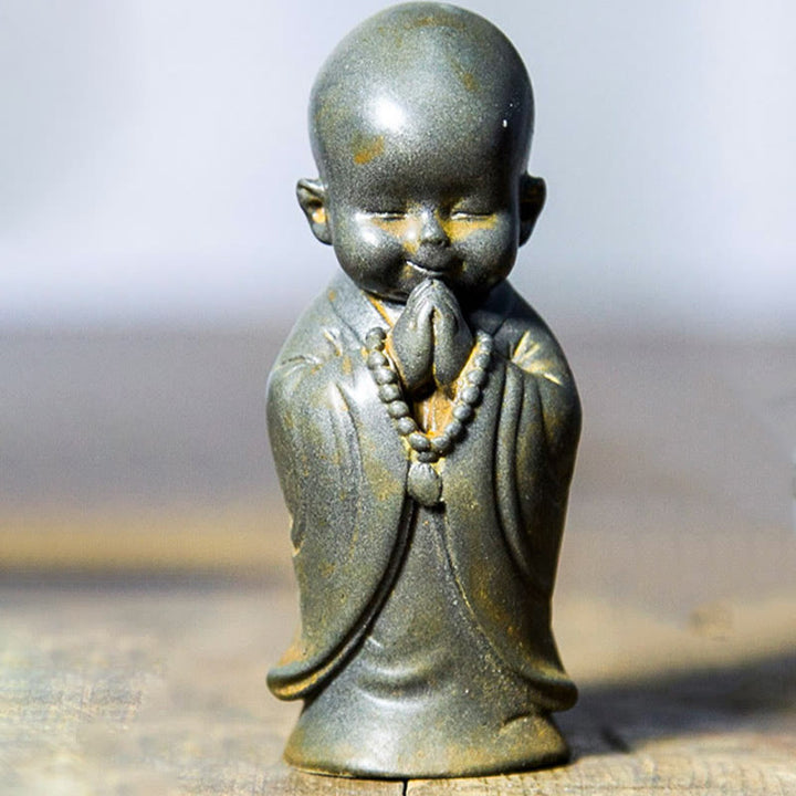 Estatua de resina fundida oxidada con polvo de hierro de un pequeño monje meditando Buddha Stones para decoración de escritorio