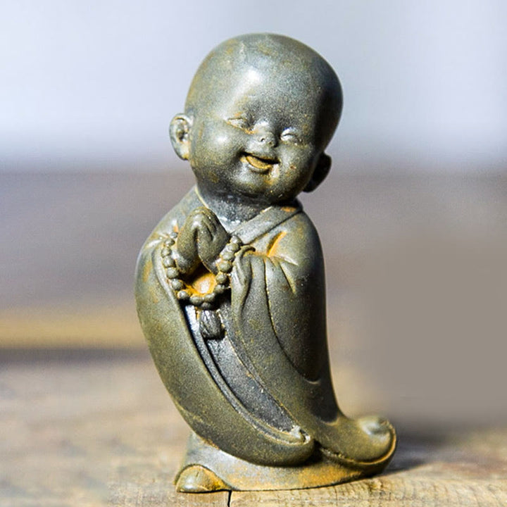 Estatua de resina fundida oxidada con polvo de hierro de un pequeño monje meditando Buddha Stones para decoración de escritorio