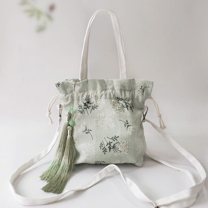 Bolso bandolera de lona con diseño de Buddha Stones, flores blancas y hojas verdes.