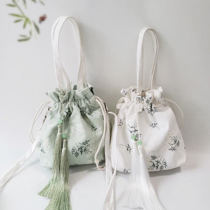 Bolso bandolera de lona con diseño de Buddha Stones, flores blancas y hojas verdes.