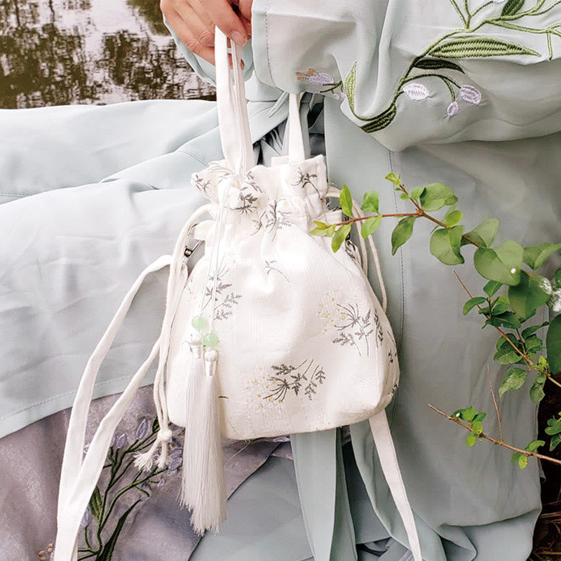 Bolso bandolera de lona con diseño de Buddha Stones, flores blancas y hojas verdes.
