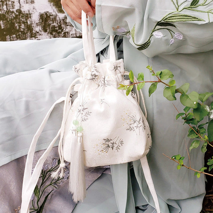Bolso bandolera de lona con diseño de Buddha Stones, flores blancas y hojas verdes.