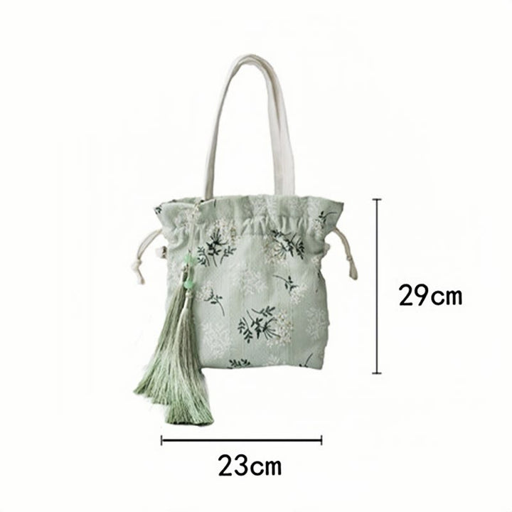 Bolso bandolera de lona con diseño de Buddha Stones, flores blancas y hojas verdes.