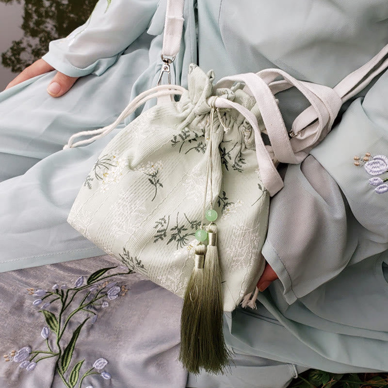 Bolso bandolera de lona con diseño de Buddha Stones, flores blancas y hojas verdes.