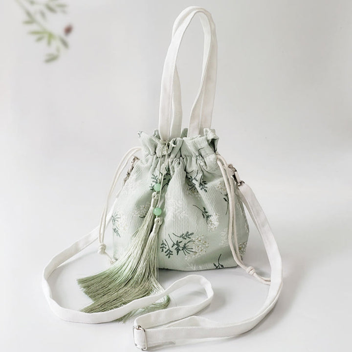 Bolso bandolera de lona con diseño de Buddha Stones, flores blancas y hojas verdes.