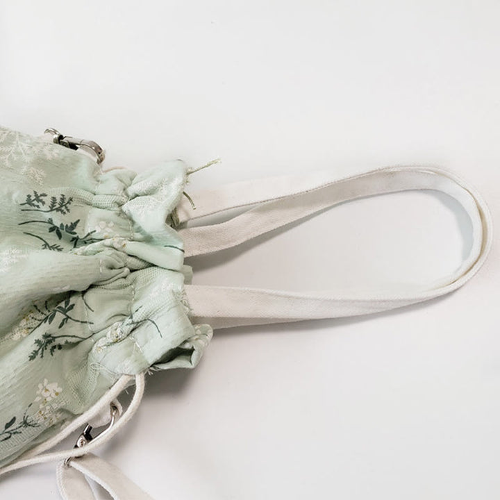 Bolso bandolera de lona con diseño de Buddha Stones, flores blancas y hojas verdes.
