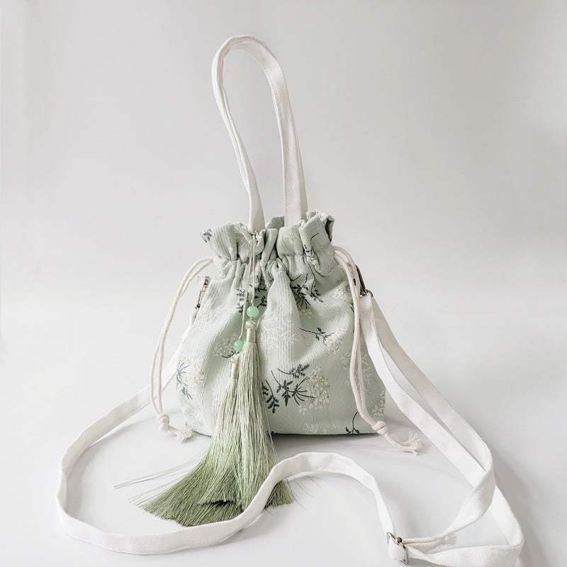 Bolso bandolera de lona con diseño de Buddha Stones, flores blancas y hojas verdes.