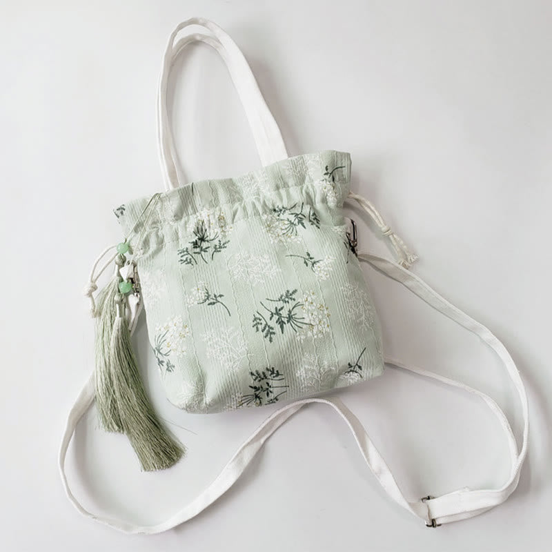 Bolso bandolera de lona con diseño de Buddha Stones, flores blancas y hojas verdes.