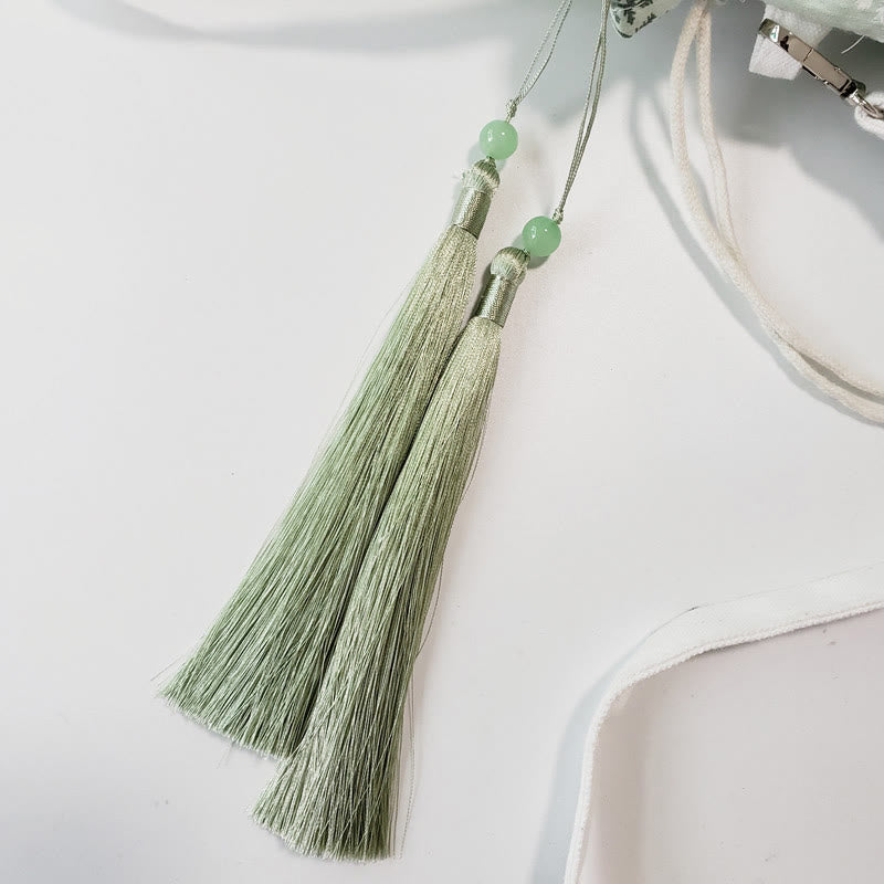 Bolso bandolera de lona con diseño de Buddha Stones, flores blancas y hojas verdes.